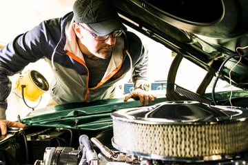 Automotive enthusiast DIYer looking at vintage engine under the hood of a vehicle