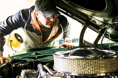 Automotive enthusiast looking at vintage engine under the hood of a classic car