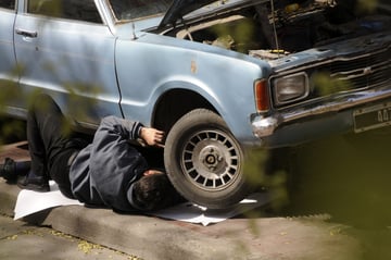 Automotive DIYer enthusiast working under a car with the help of DIY resources