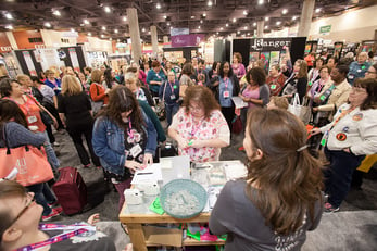 Crowd gathers at a crafting convention demonstration