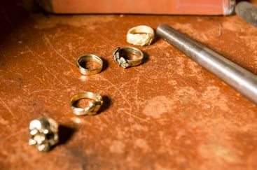 Metal wax cast jewelry laid out on a workbench with jewelry making tool