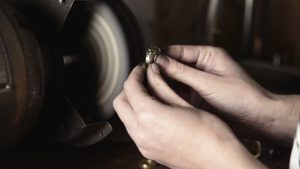Jewelry maker grinding a bronze ring on a sanding tool