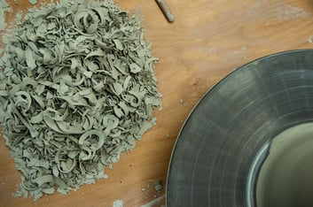 Clay shavings on a ceramicist's work table next to a pottery wheel