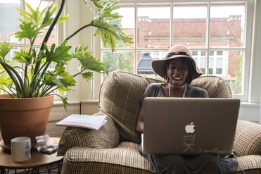 Smiling woman using Pinterest on a laptop in a maker studio in front of a window