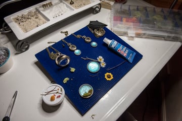 Jewelry making products tools and supplies laid out on a work table while flower resin jewelry cures