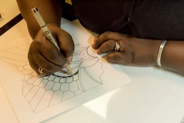 Paper crafter drawing a design on to a large card using a fine tip pen