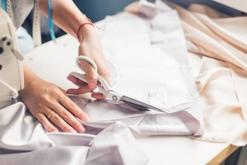 Sewist creating a garment with a sewing pattern and scissors