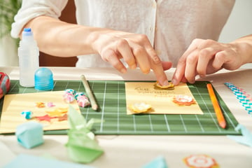 Paper crafter using craft tools and paper to create scrapbooking embellishments