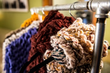 Knitted scarves in multiple colors hanging on a clothes rack