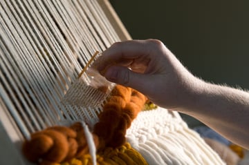 Fiber artist creating a weaving on a loom using a tutorial