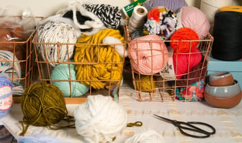 Fiber artist supply basket filled with colorful yarn and scissors