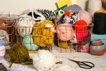 Fiber art supply basket filled with different colors and textures of yarn