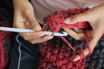 Fiber artist working on a project with a hooked crochet needle