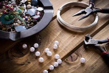 Jewlery making beads, wire, and supplies sitting on a wooden table