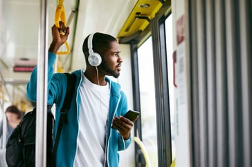 Man with headphones listening to a podcast on his phone during his bus commute