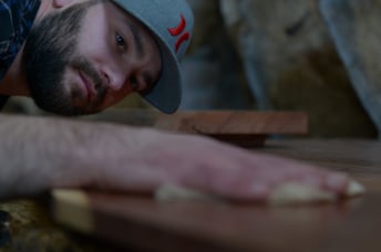Woodworker demonstrating how to insert a slab into a planer 