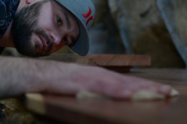 Woodcrafter finishing a live edge table by hand