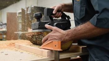 Woodworker using a sander on a live edge piece of wood