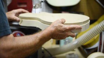 Luthier Dave Lackey trimming a guitar body using a template