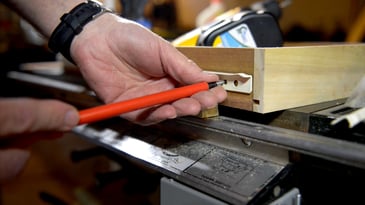 Woodworker demonstrating screwing a track into a dresser drawer