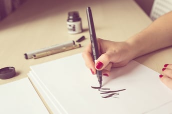 Female hand practicing calligraphy and hand lettering with a brush pen